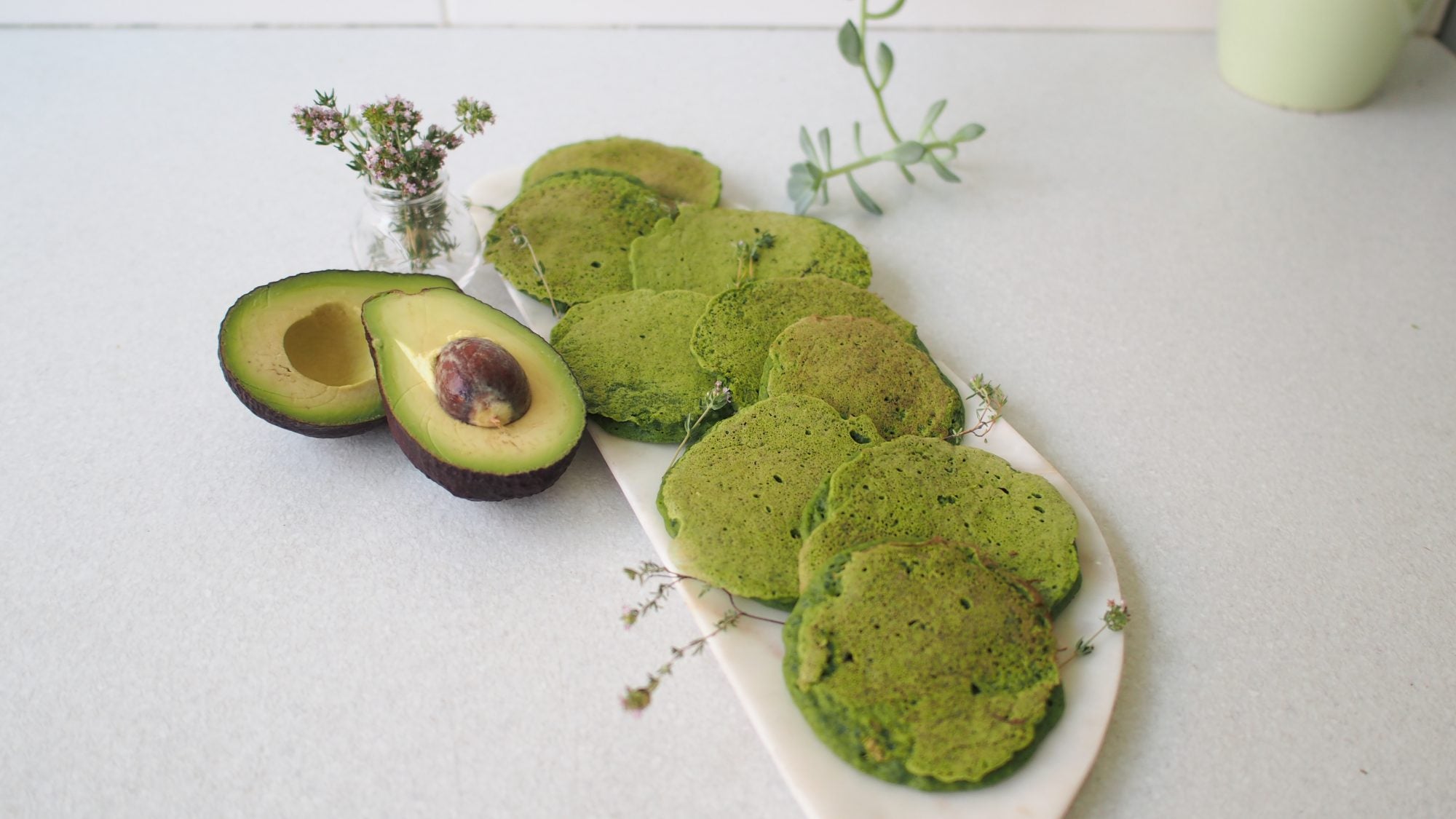 A plate of green pancakes with avocado